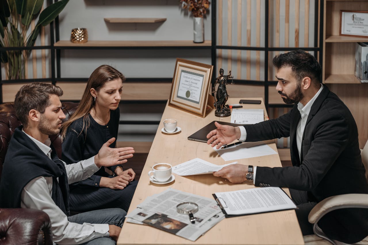 services-01 Lawyer consulting clients in an office. Documents and coffee on the table.