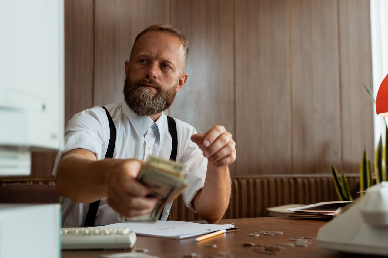 services-02 Businessman in a corporate office handling a stack of cash at his desk.